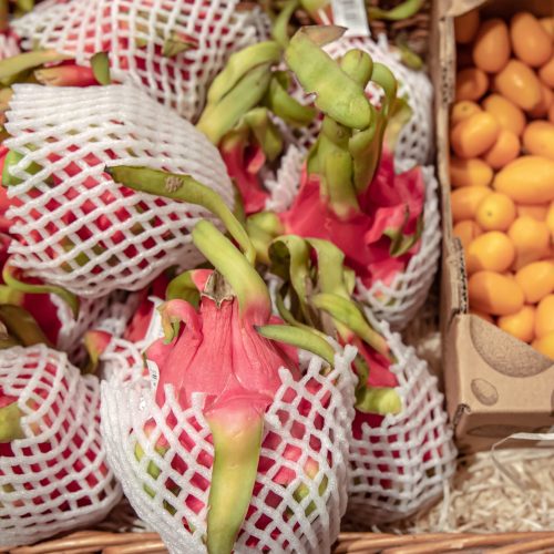 Close up of dragon fruit and kinkan on a supermarket counter.