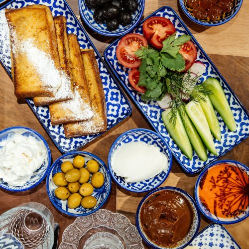 top view of fresh salad with cucumbers herbs and tomatoes served with toasts and black olives on the table